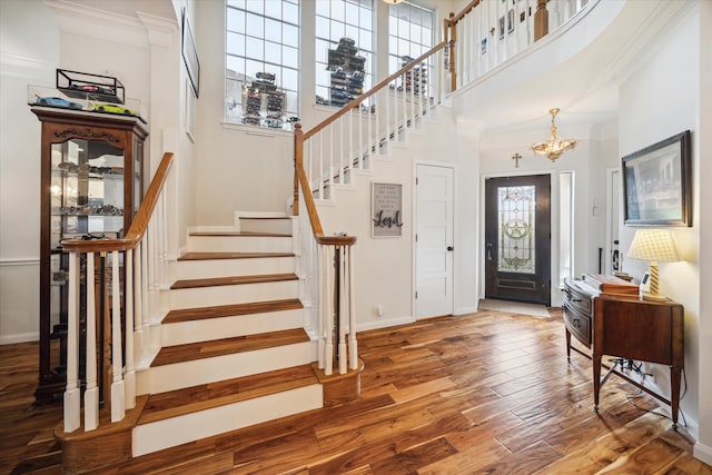 entrance foyer with hardwood / wood-style floors, ornamental molding, a high ceiling, and an inviting chandelier