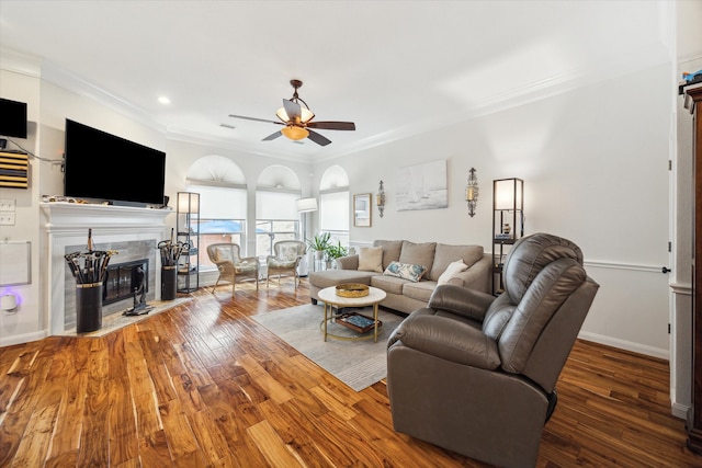 living room featuring hardwood / wood-style flooring, ceiling fan, ornamental molding, and a fireplace