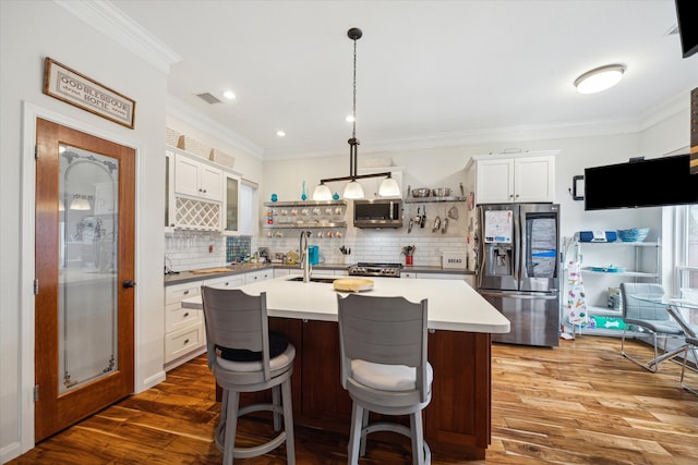 kitchen featuring white cabinetry, dark wood-type flooring, pendant lighting, a center island with sink, and appliances with stainless steel finishes