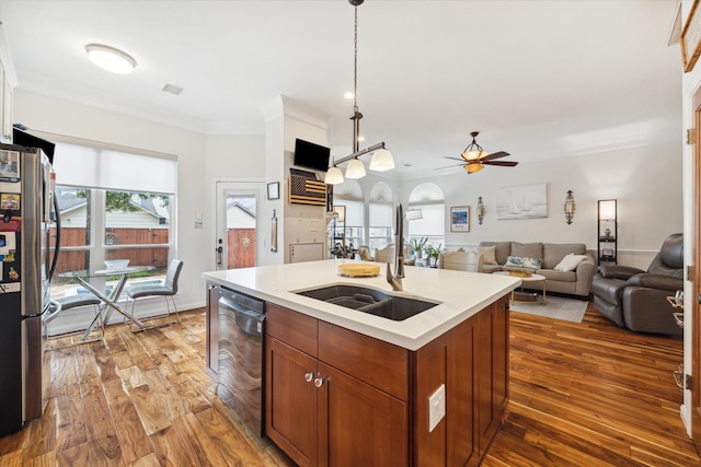 kitchen featuring hanging light fixtures, ornamental molding, light wood-type flooring, an island with sink, and stainless steel appliances