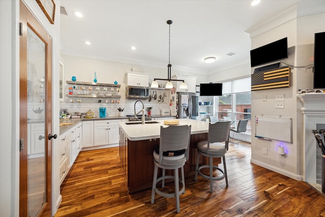 kitchen with pendant lighting, dark hardwood / wood-style floors, stainless steel appliances, and a kitchen island with sink