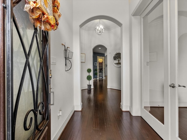 interior space with a chandelier, dark wood-type flooring, and ornamental molding