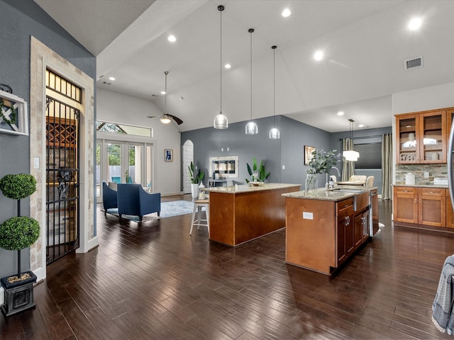 kitchen featuring a kitchen breakfast bar, decorative light fixtures, a kitchen island with sink, and dark hardwood / wood-style floors