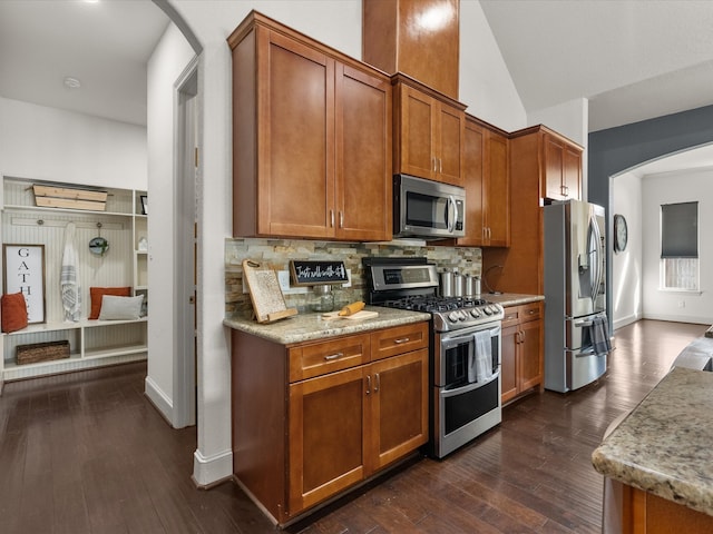 kitchen with backsplash, dark hardwood / wood-style flooring, vaulted ceiling, and appliances with stainless steel finishes