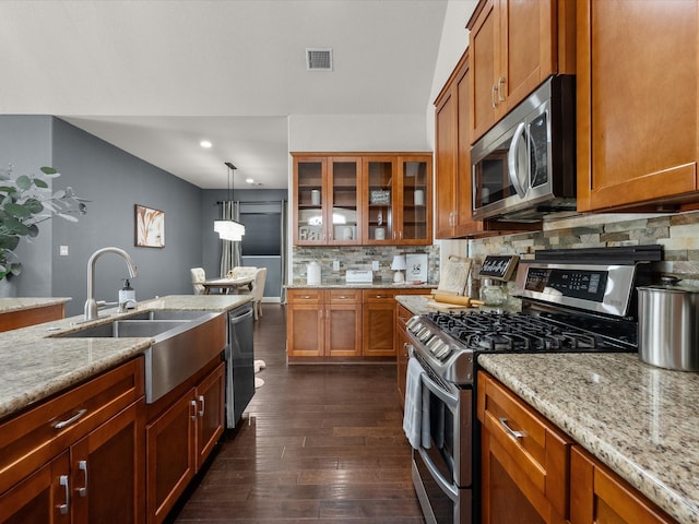 kitchen featuring light stone countertops, tasteful backsplash, stainless steel appliances, decorative light fixtures, and dark hardwood / wood-style floors