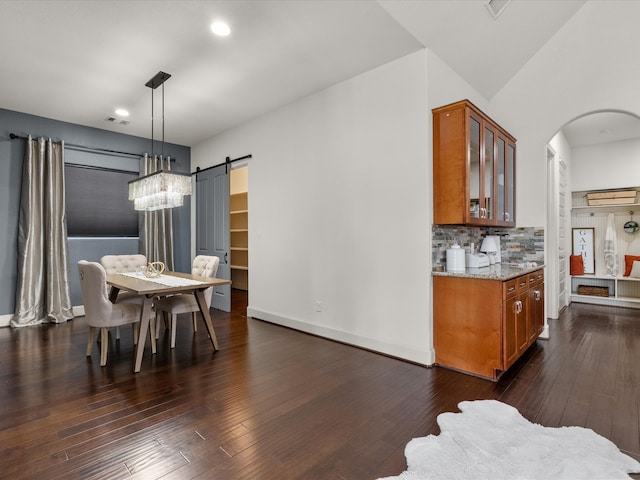 dining room with a barn door and dark wood-type flooring