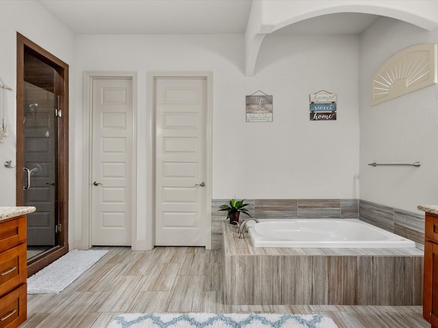 bathroom with vanity and shower with separate bathtub