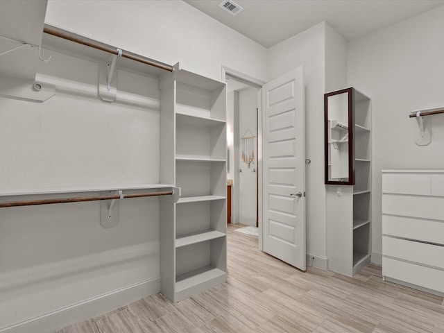 walk in closet with light hardwood / wood-style flooring