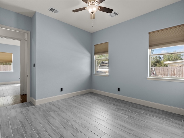 unfurnished room featuring ceiling fan, plenty of natural light, and light wood-type flooring