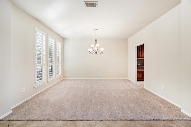 spare room featuring light colored carpet and an inviting chandelier