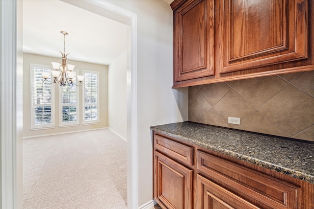 interior space featuring carpet, dark stone counters, decorative backsplash, decorative light fixtures, and a chandelier