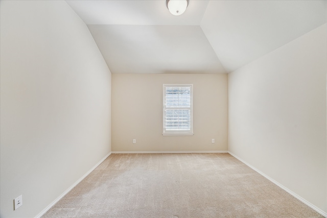 spare room featuring light colored carpet and lofted ceiling