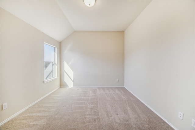 empty room with light colored carpet and vaulted ceiling