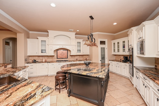 kitchen featuring pendant lighting, a kitchen island, white cabinets, and dark stone countertops