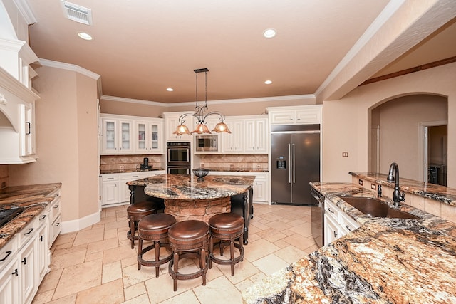 kitchen featuring a center island, backsplash, dark stone counters, a kitchen breakfast bar, and built in appliances