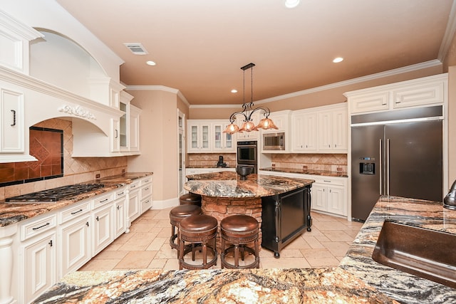 kitchen with built in appliances, a kitchen island, and dark stone countertops