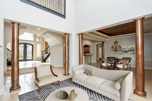 living room featuring ornate columns, french doors, and a towering ceiling