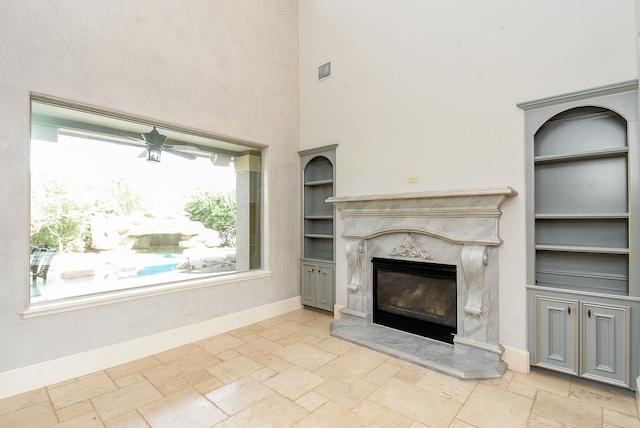 unfurnished living room featuring built in features, a fireplace, and a high ceiling