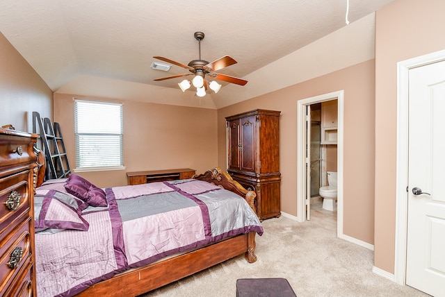 carpeted bedroom with a textured ceiling, connected bathroom, vaulted ceiling, and ceiling fan