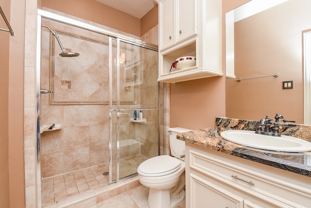 bathroom featuring tile patterned flooring, vanity, toilet, and a shower with door