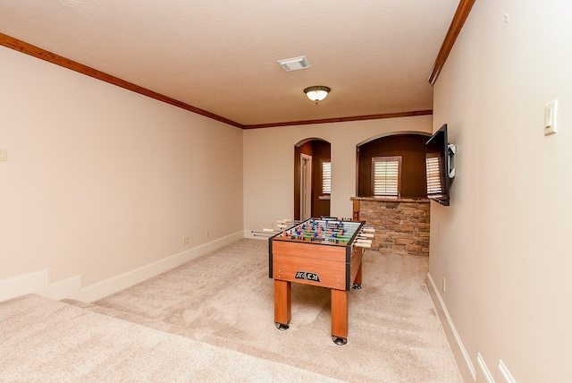 game room with a textured ceiling, light colored carpet, and ornamental molding