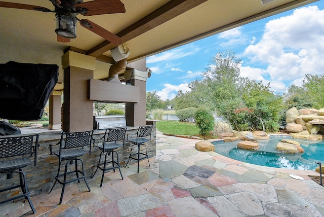 view of patio with ceiling fan, exterior kitchen, a jacuzzi, area for grilling, and a bar