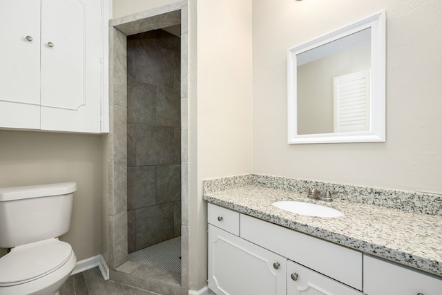 bathroom featuring vanity, toilet, and a tile shower