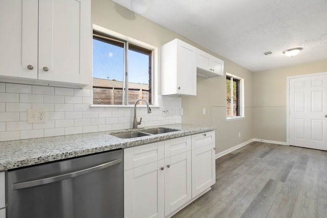 kitchen featuring sink, stainless steel dishwasher, light wood-type flooring, light stone counters, and white cabinetry