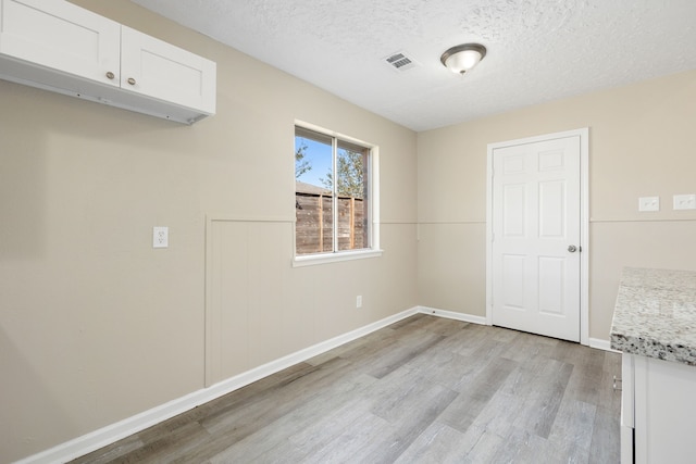 interior space with a textured ceiling and light wood-type flooring