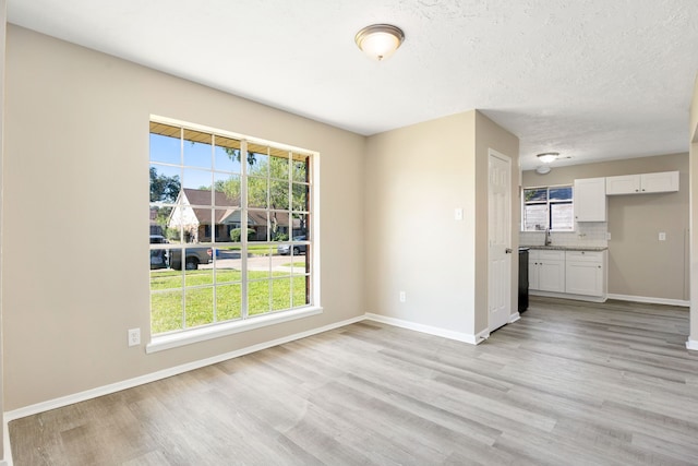 unfurnished room with a textured ceiling and light hardwood / wood-style flooring