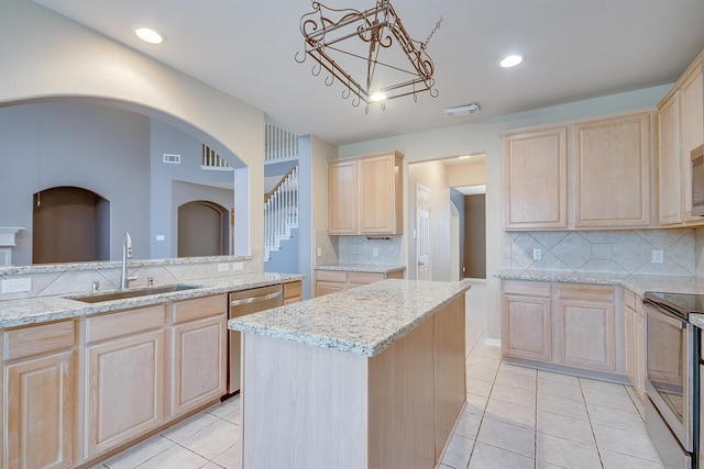 kitchen featuring decorative backsplash, appliances with stainless steel finishes, sink, light brown cabinets, and a center island