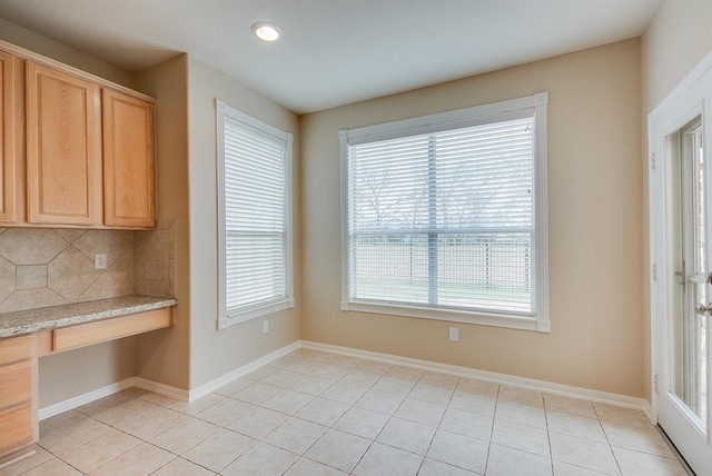 unfurnished dining area with light tile patterned flooring and built in desk