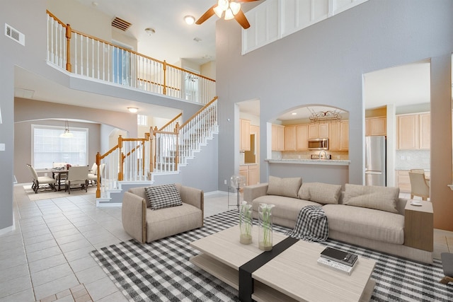 living room featuring ceiling fan, light tile patterned flooring, and a high ceiling