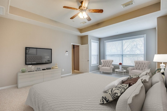 carpeted bedroom with ceiling fan and a tray ceiling