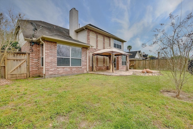 rear view of house featuring a gazebo, a lawn, and a patio