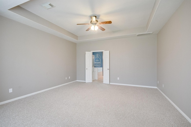 carpeted empty room featuring a tray ceiling and ceiling fan