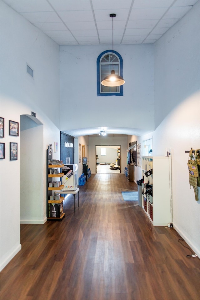 hall featuring a drop ceiling, a high ceiling, and dark hardwood / wood-style floors