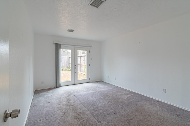 carpeted empty room with french doors and a textured ceiling