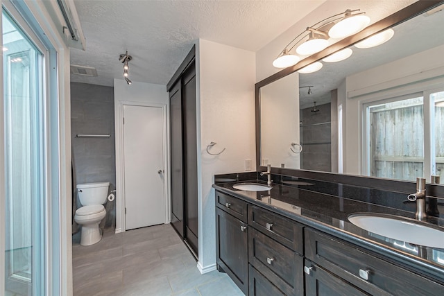 bathroom featuring toilet, vanity, a textured ceiling, and walk in shower