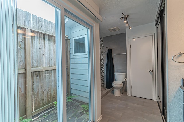 bathroom with toilet and a textured ceiling