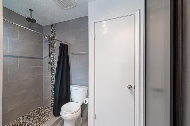 bathroom featuring toilet, a textured ceiling, and walk in shower