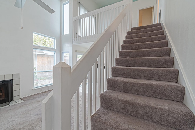 staircase with carpet, plenty of natural light, ceiling fan, and a high ceiling