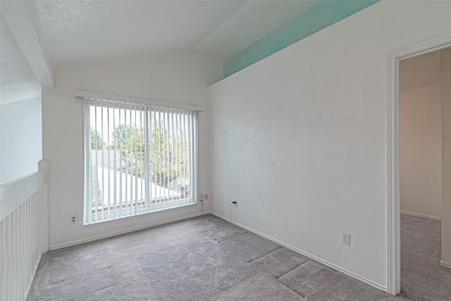 carpeted spare room with vaulted ceiling