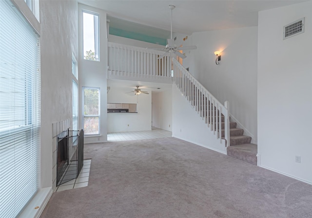 unfurnished living room with ceiling fan, a high ceiling, and light carpet