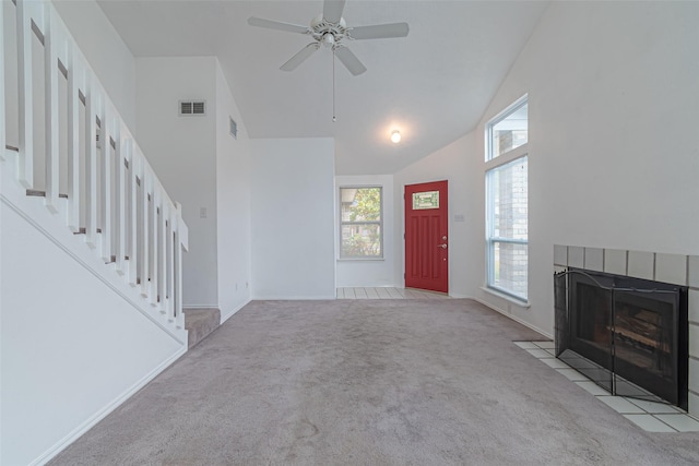 unfurnished living room featuring light carpet, a tile fireplace, high vaulted ceiling, and ceiling fan