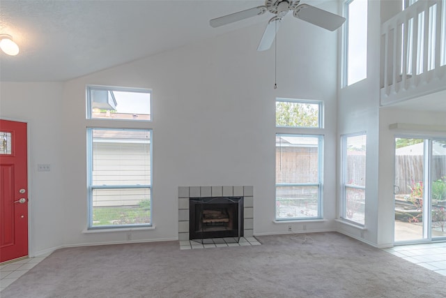 unfurnished living room with light carpet, a healthy amount of sunlight, high vaulted ceiling, and a tile fireplace