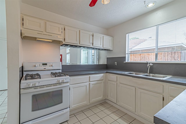 kitchen featuring white cabinets, white gas range, sink, and light tile patterned floors