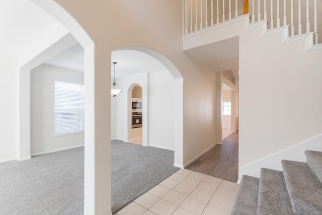 corridor with stairway, light tile patterned floors, baseboards, and light carpet