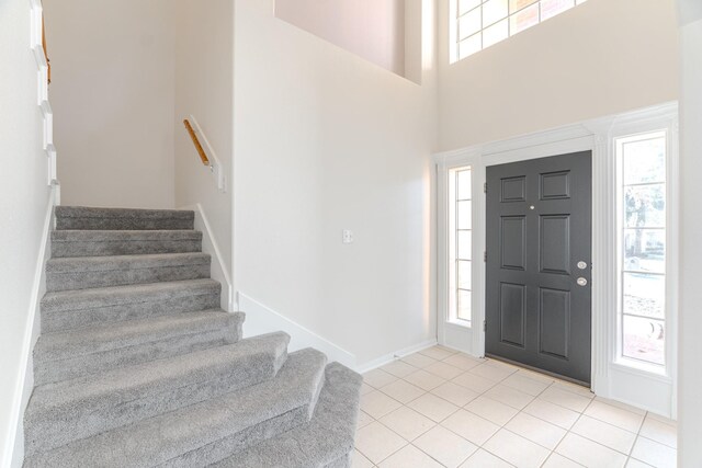 foyer entrance featuring light tile patterned flooring, a towering ceiling, and a wealth of natural light