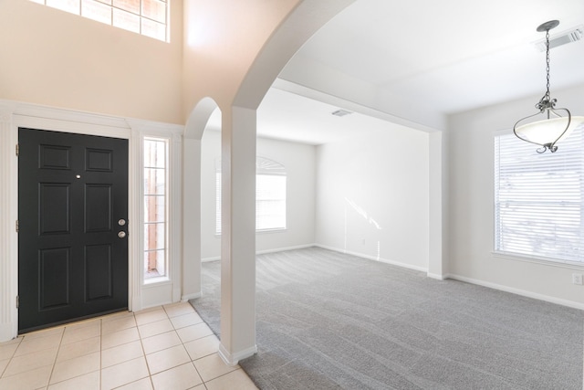 entryway featuring visible vents, light colored carpet, arched walkways, and a healthy amount of sunlight